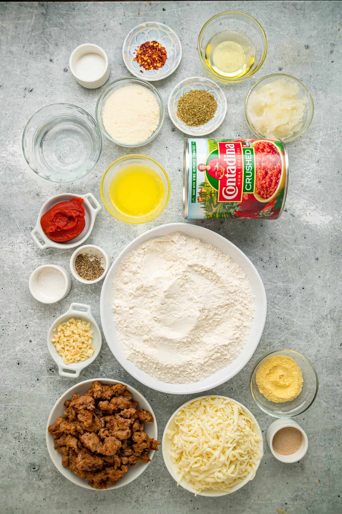 This Chicago-Style Deep Dish Pizza recipe features a buttery, flaky crust topped with mozzarella, crumbled sausage, & a savory tomato sauce. Overhead view of ingredients needed to make Chicago-style deep dish pizza