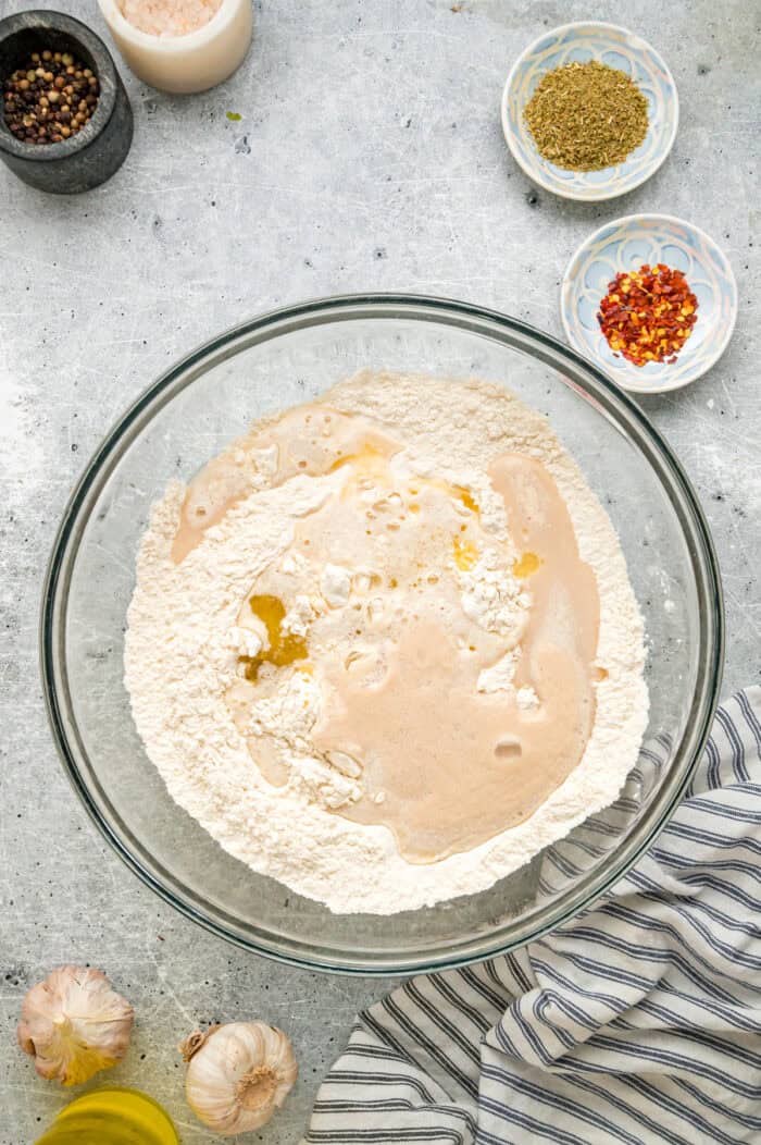 This Chicago-Style Deep Dish Pizza recipe features a buttery, flaky crust topped with mozzarella, crumbled sausage, & a savory tomato sauce. Pizza dough ingredients in a bowl