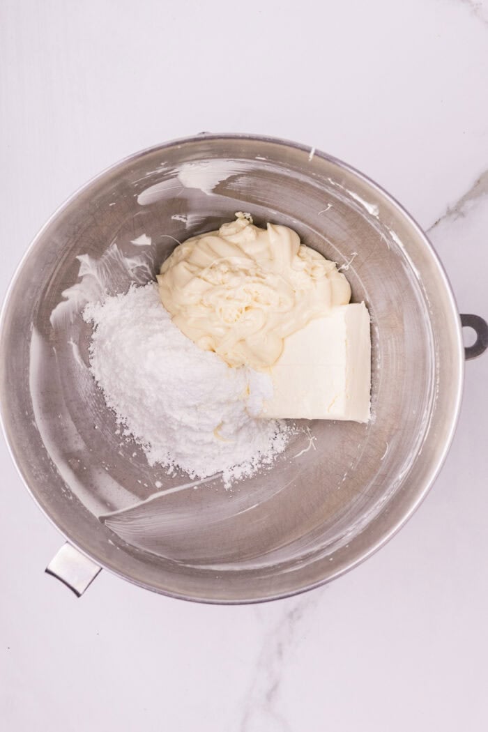 Powdered sugar, sour cream, and cream cheese n a mixing bowl