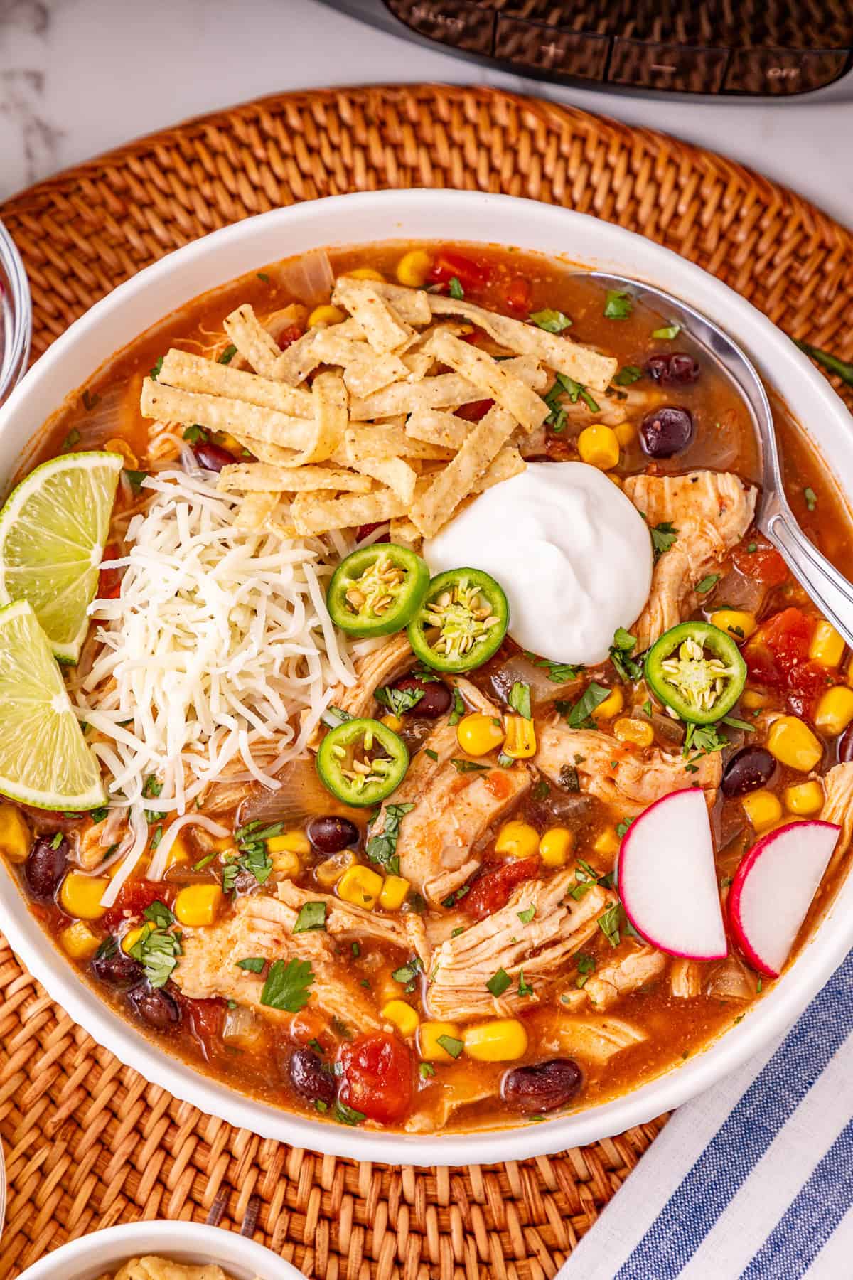 Chicken, beans, diced tomatoes and green chilies, and corn are slow-cooked in enchilada sauce broth to make Crockpot Chicken Enchilada Soup. Overhead view of a bowl of crockpot chicken enchilada soup