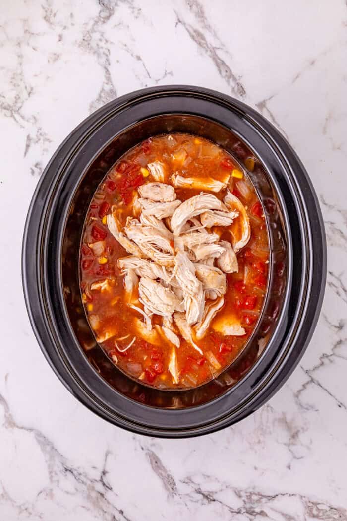 Chicken, beans, diced tomatoes and green chilies, and corn are slow-cooked in enchilada sauce broth to make Crockpot Chicken Enchilada Soup. Shredded chicken added back to the crockpot of enchilada soup