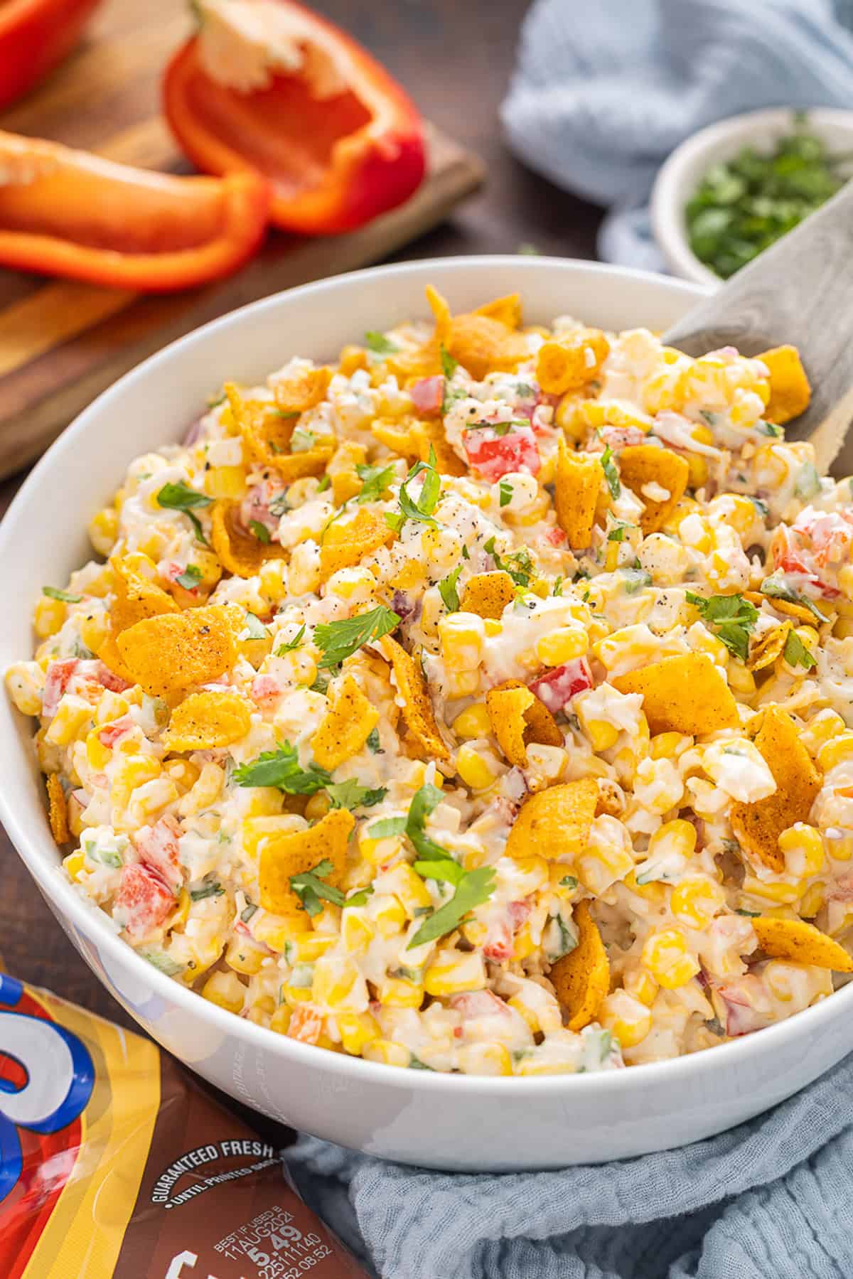 Frito Corn Salad is fun, flavorful, and the perfect combination of crunchy and creamy, with diced veggies and crushed Fritos. Close up of a bowl of Frito corn salad