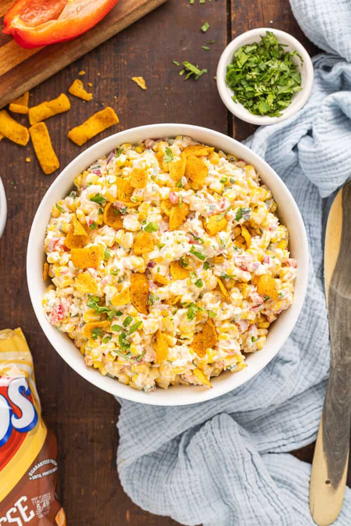 Frito Corn Salad is fun, flavorful, and the perfect combination of crunchy and creamy, with diced veggies and crushed Fritos. Overhead view of a bowl of Frito corn salad