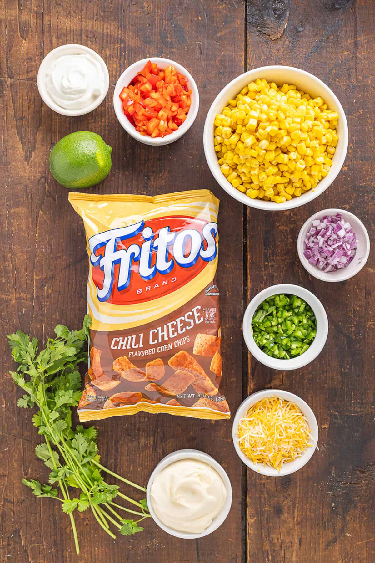 Frito Corn Salad is fun, flavorful, and the perfect combination of crunchy and creamy, with diced veggies and crushed Fritos. Overhead view of ingredients needed to make Frito corn salad