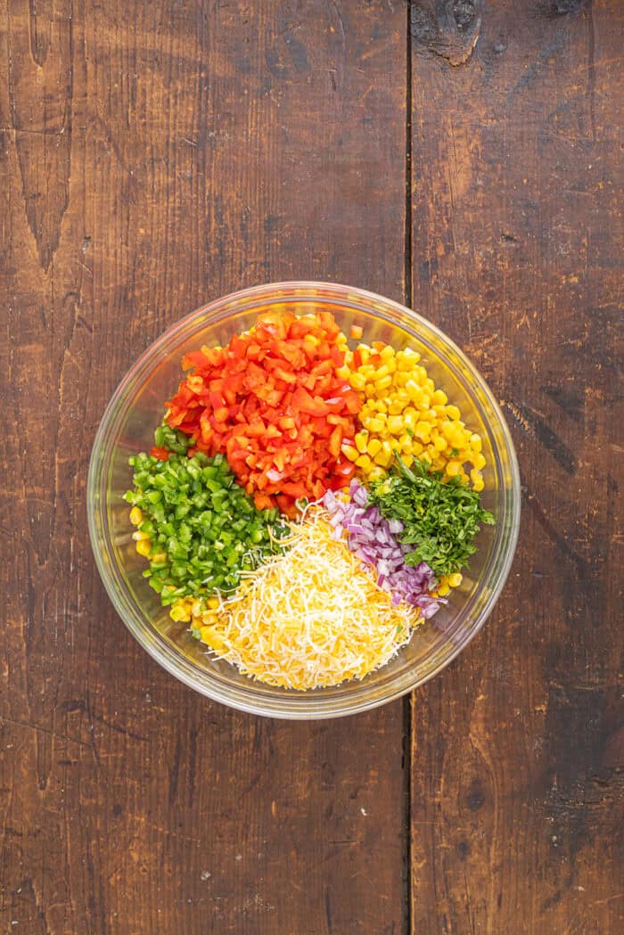 Frito Corn Salad is fun, flavorful, and the perfect combination of crunchy and creamy, with diced veggies and crushed Fritos. Corn, diced peppers, and onion in a bowl