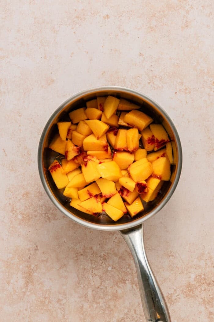 Fresh peaches are turned into a compote and swirled into a mixture of sweetened condensed milk & heavy cream in this No-Churn Peach Ice Cream. Diced peaches in a saucepan