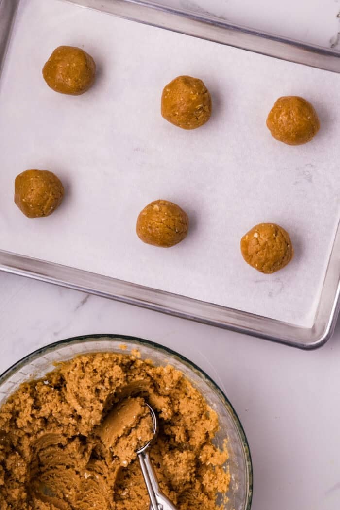 These soft and chewy Peanut Butter Marshmallow Cookies are loaded with rich peanut butter flavor and a marshmallow surprise. Balls of peanut butter cookie dough on a baking sheet