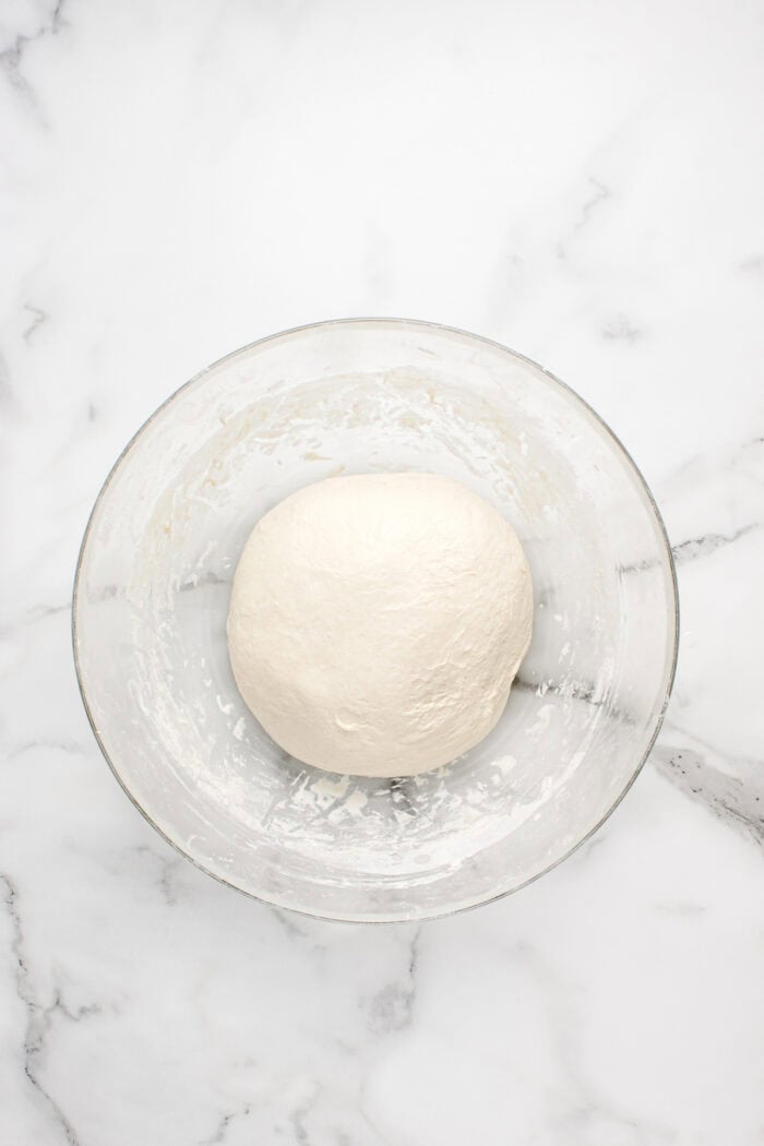 Made with an active sourdough starter, pantry staples, and a simple process, this Sourdough Bread recipe is perfect for beginners. A ball of sourdough bread dough in a bowl