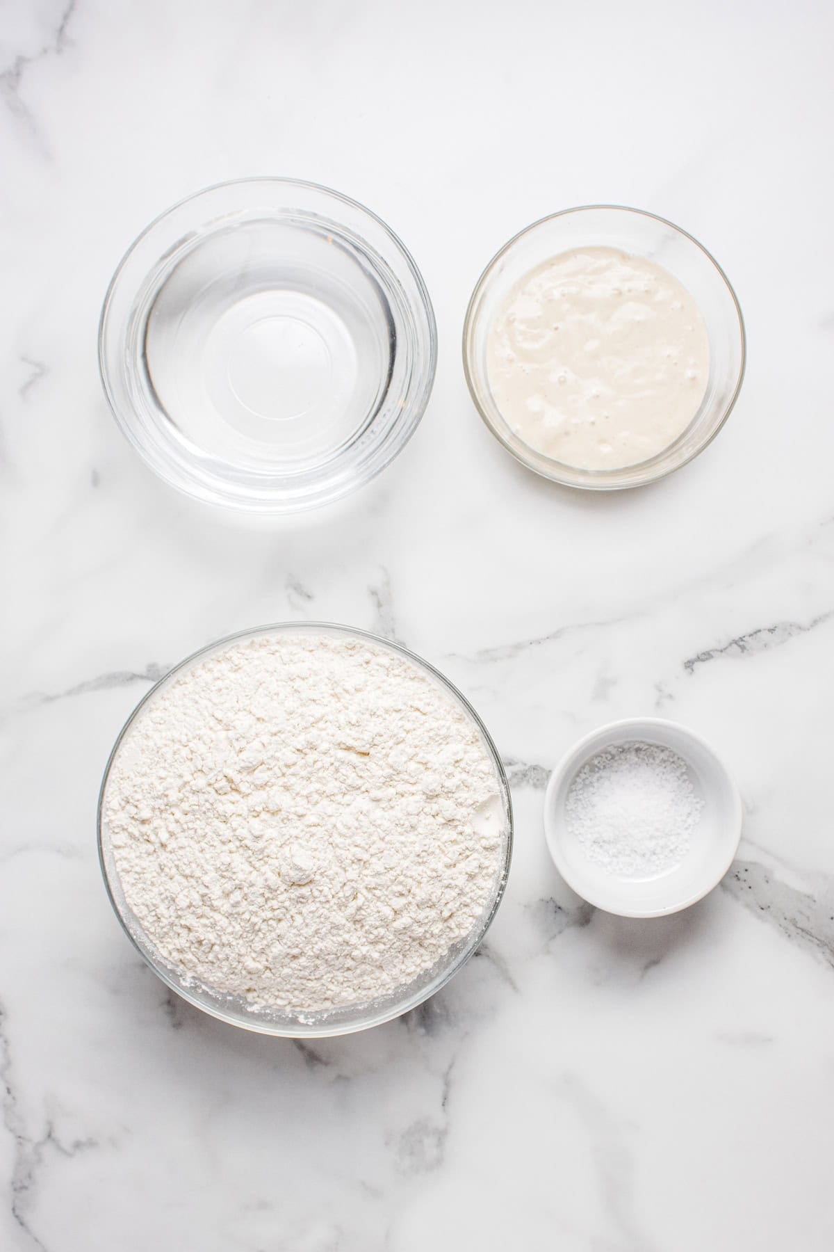 Made with an active sourdough starter, pantry staples, and a simple process, this Sourdough Bread recipe is perfect for beginners. Overhead view of ingredients needed to make sourdough bread