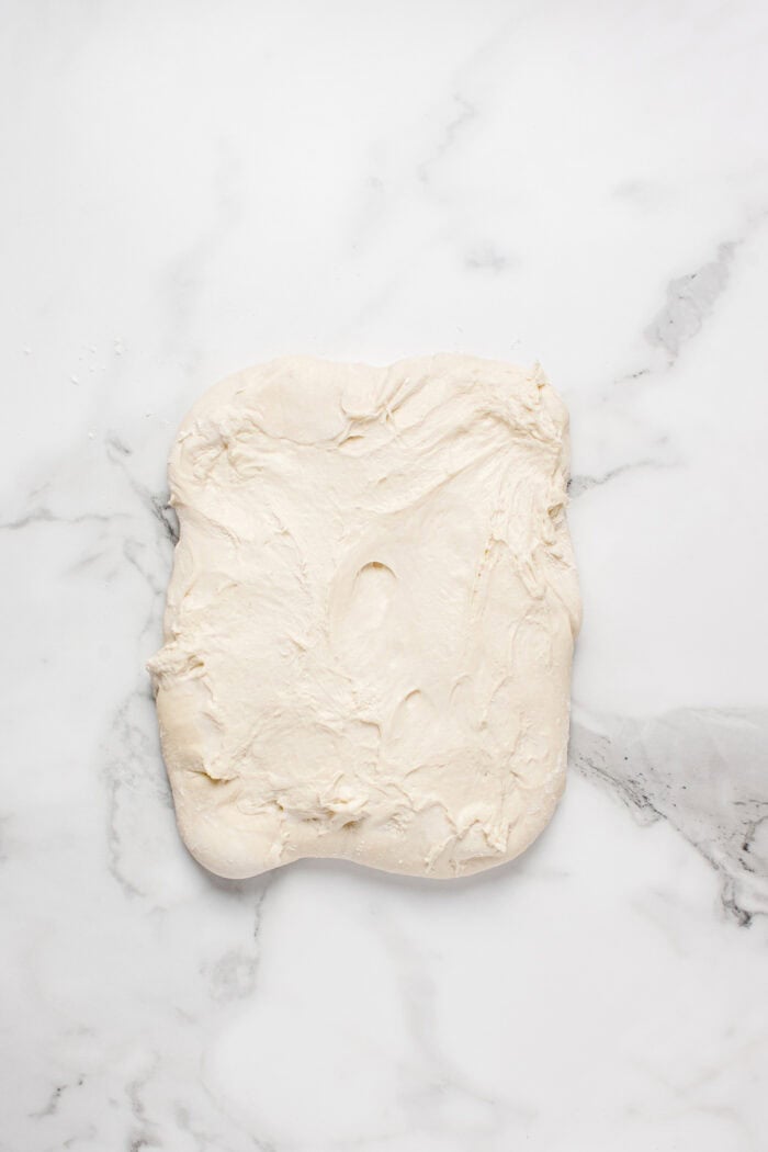 Made with an active sourdough starter, pantry staples, and a simple process, this Sourdough Bread recipe is perfect for beginners. Sourdough bread dough rolled into a rectangle