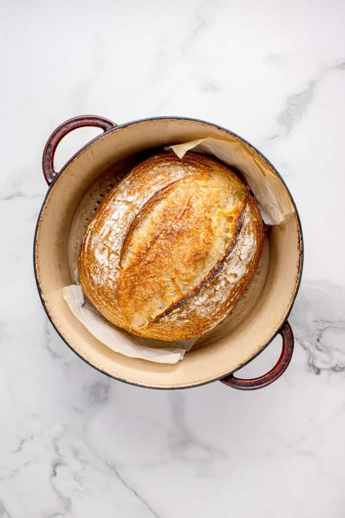 Made with an active sourdough starter, pantry staples, and a simple process, this Sourdough Bread recipe is perfect for beginners. Overhead view of freshly baked sourdough bread in a Dutch oven