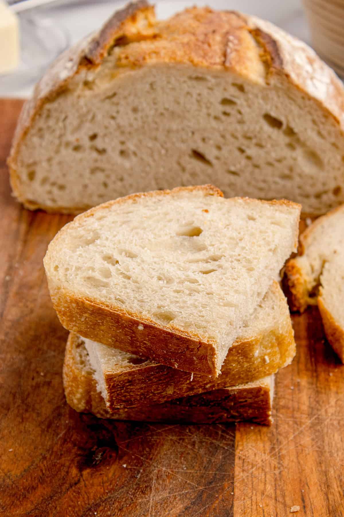 Made with an active sourdough starter, pantry staples, and a simple process, this Sourdough Bread recipe is perfect for beginners. Halved sliced of sourdough bread stacked on each other in front of a loaf
