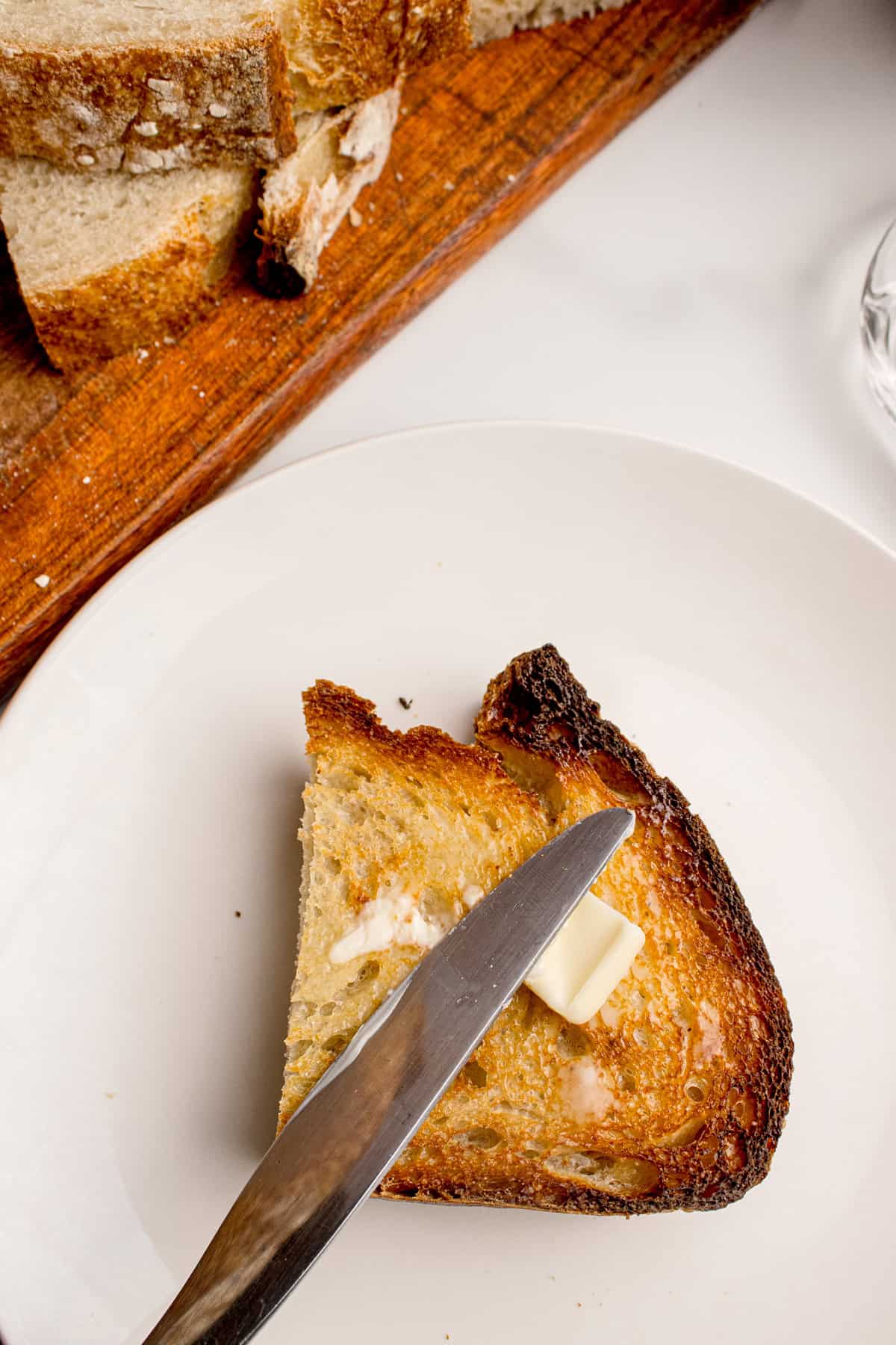 Made with an active sourdough starter, pantry staples, and a simple process, this Sourdough Bread recipe is perfect for beginners. Spreading butter on half a slice of toasted sourdough bread
