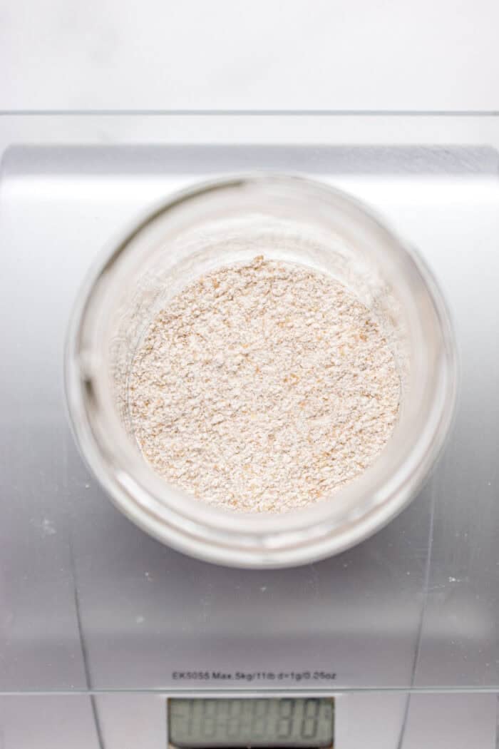 This easy sourdough starter recipe walks you through the process day-by-day with images. Great for beginners! Weighing flour in a scale