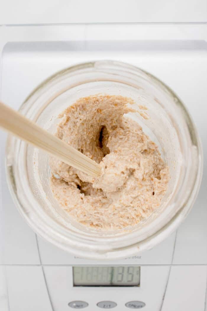 This easy sourdough starter recipe walks you through the process day-by-day with images. Great for beginners! Mixing sourdough starter in a glass jar