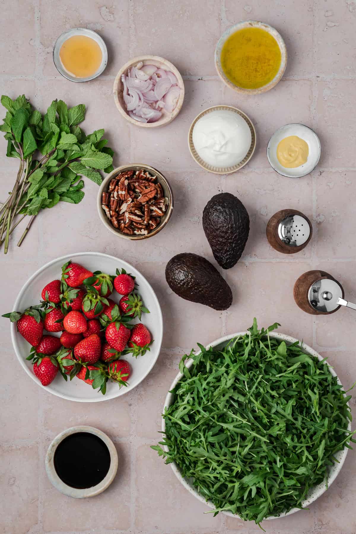 Strawberry Arugula Salad is perfect for summer, with peppery arugula, fresh strawberries, creamy burrata, crunchy pecans & avocado. Overhead view of ingredients needed to make strawberry arugula salad