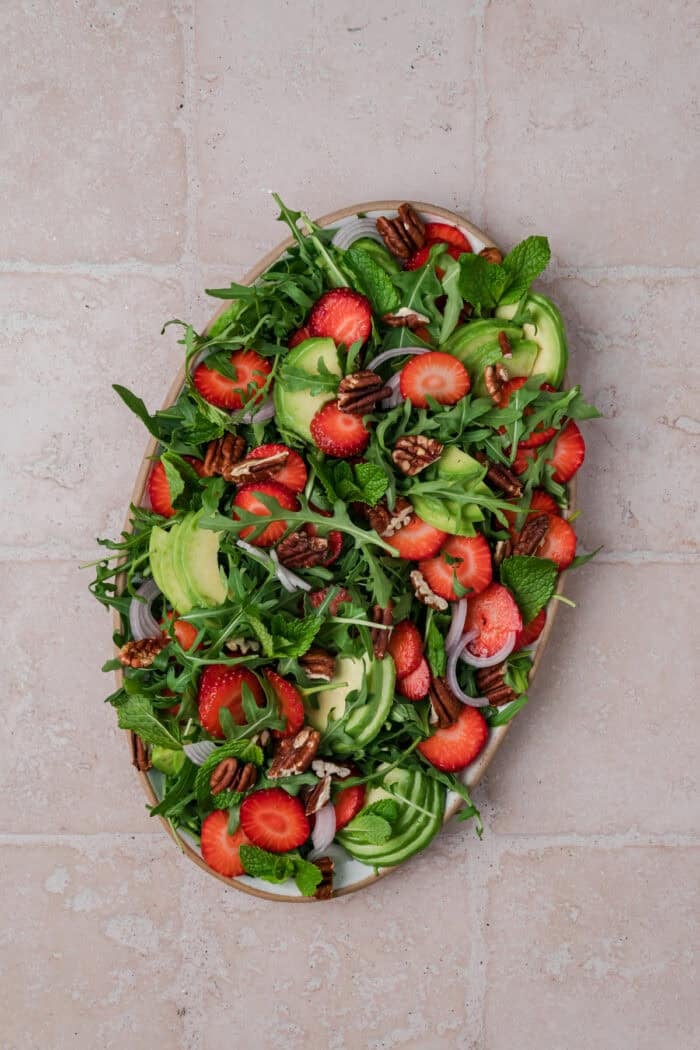 Strawberry Arugula Salad is perfect for summer, with peppery arugula, fresh strawberries, creamy burrata, crunchy pecans & avocado. Strawberries and avocado slices on top of a bed of arugula
