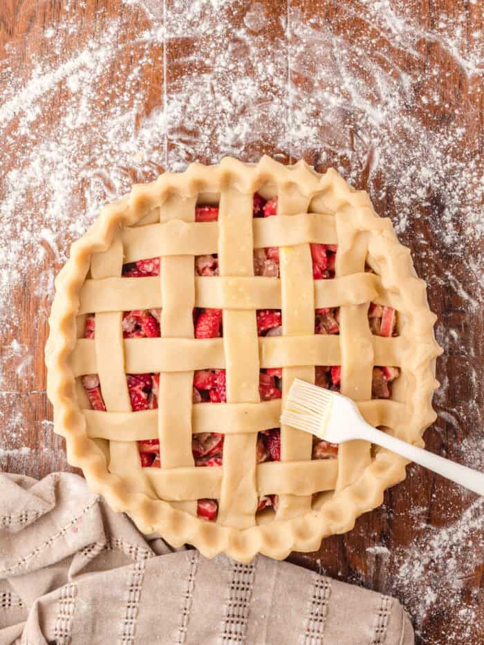 Brushing the top of a lattice pie crust with butter