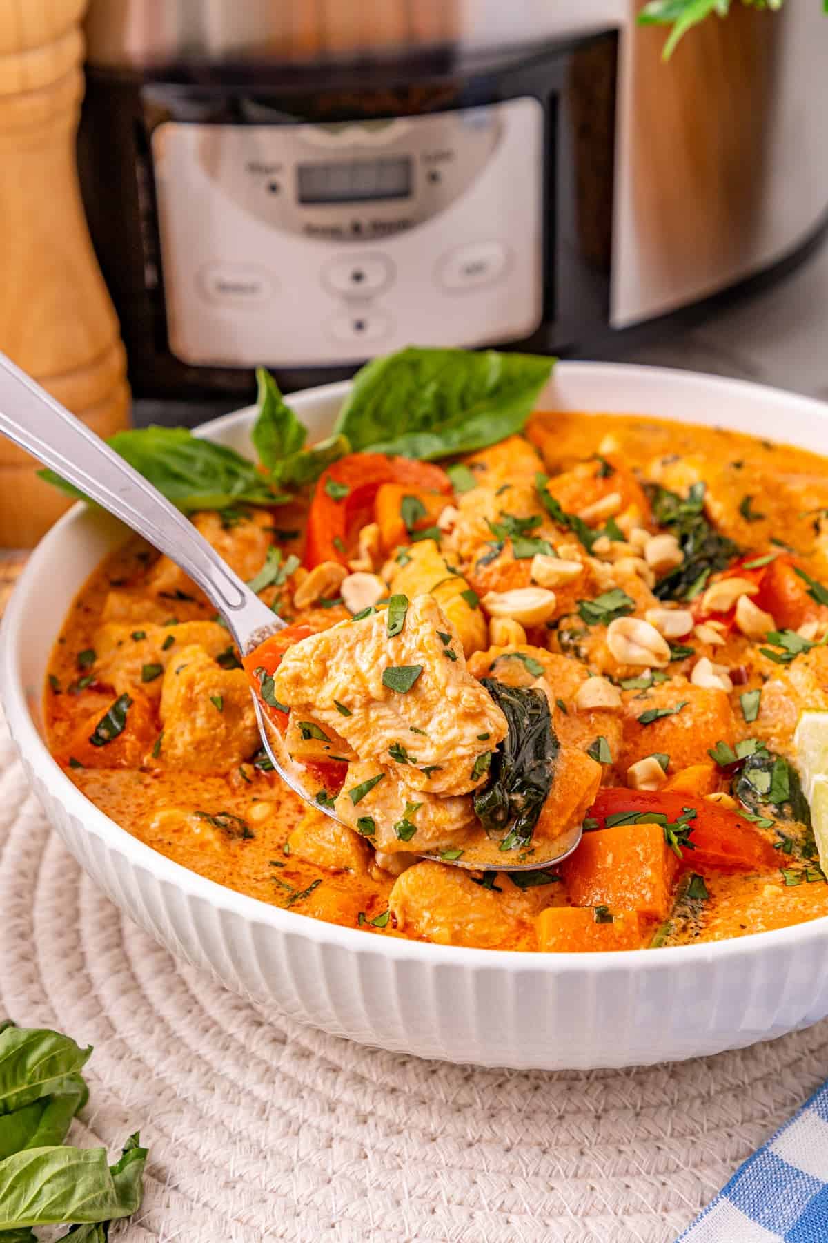 Chicken, sweet potatoes, coconut milk, curry paste, and peanut butter are slow-cooked to make this easy Thai Red Curry Chicken. A spoon in a bowl of Thai red curry chicken