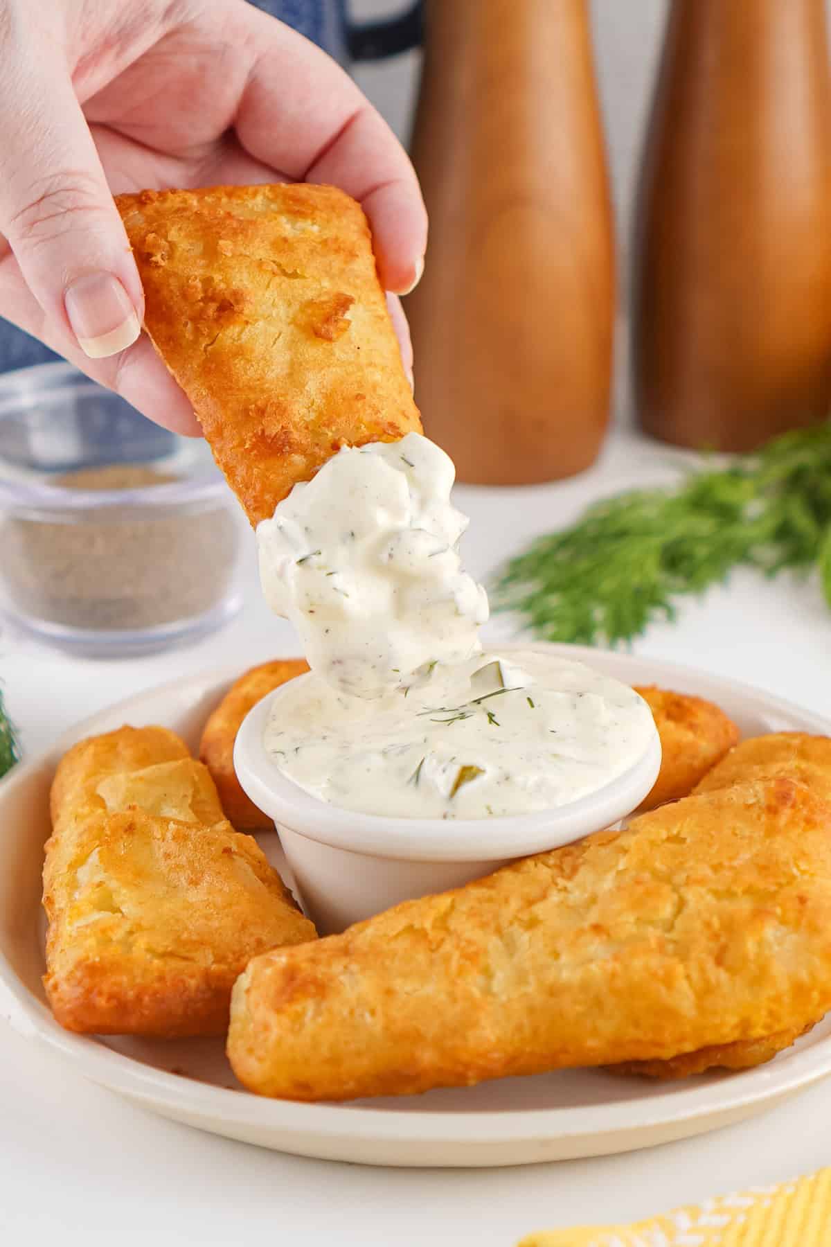 A fish stick being dipped into Homemade Tartar Sauce