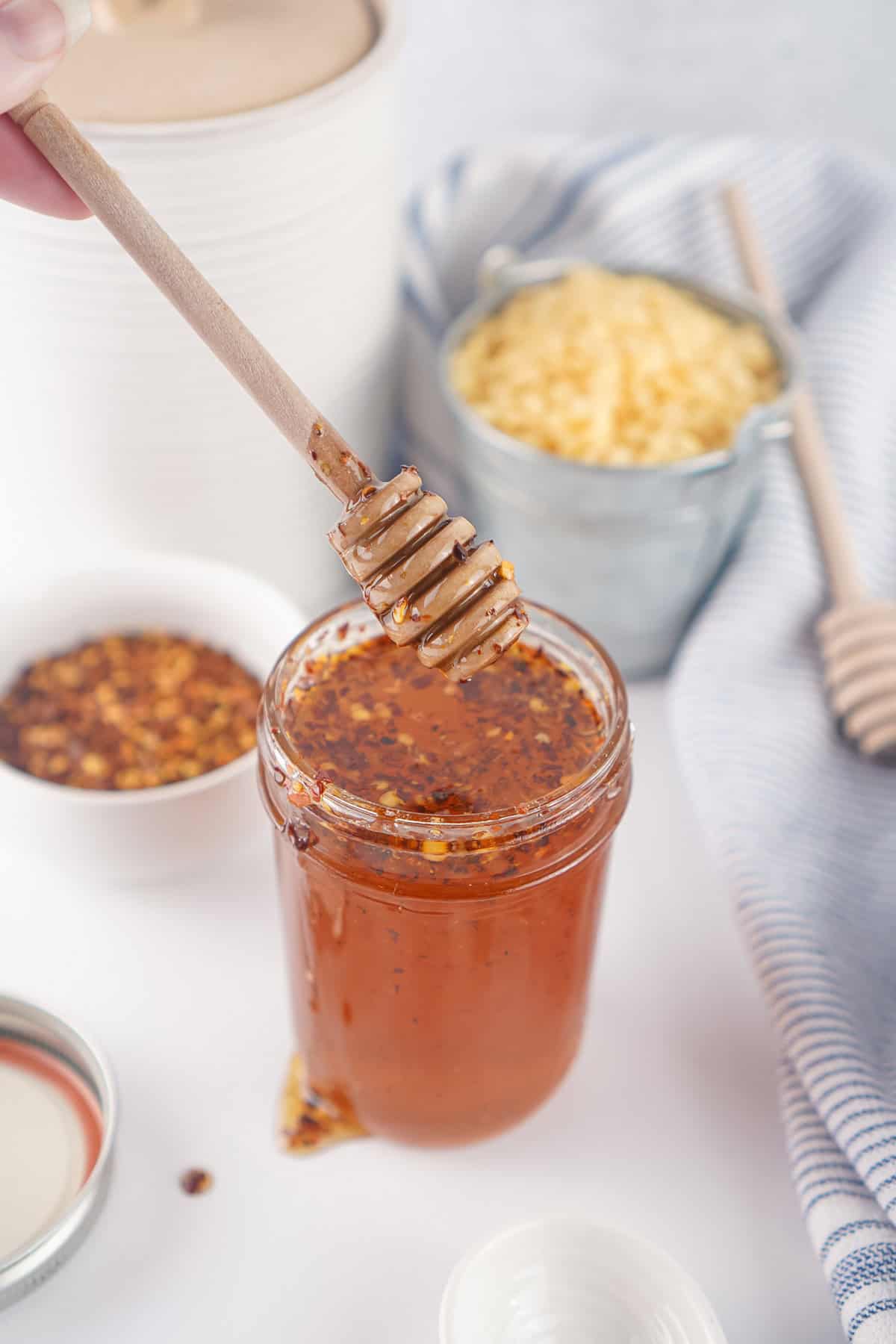 This Hot Honey recipe is made with just 3 ingredients in 7 minutes. It’s ridiculously easy and so much cheaper than buying it at the store. A honey stirrer over a jar of homemade hot hot