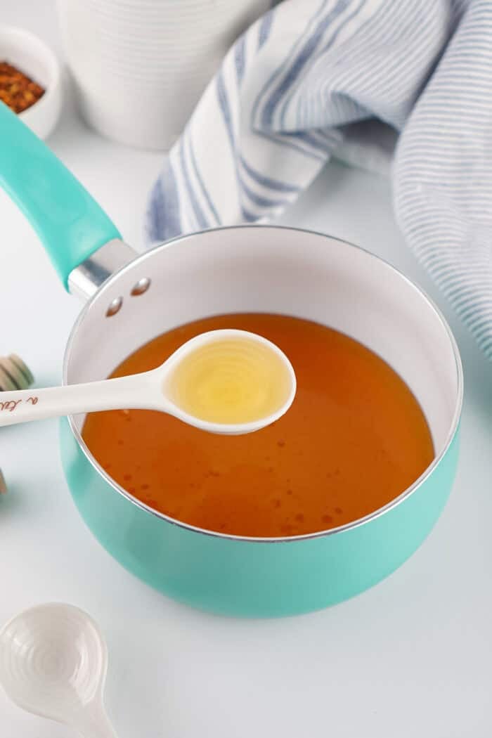 This Hot Honey recipe is made with just 3 ingredients in 7 minutes. It’s ridiculously easy and so much cheaper than buying it at the store. Vinegar being added to a saucepan of honey