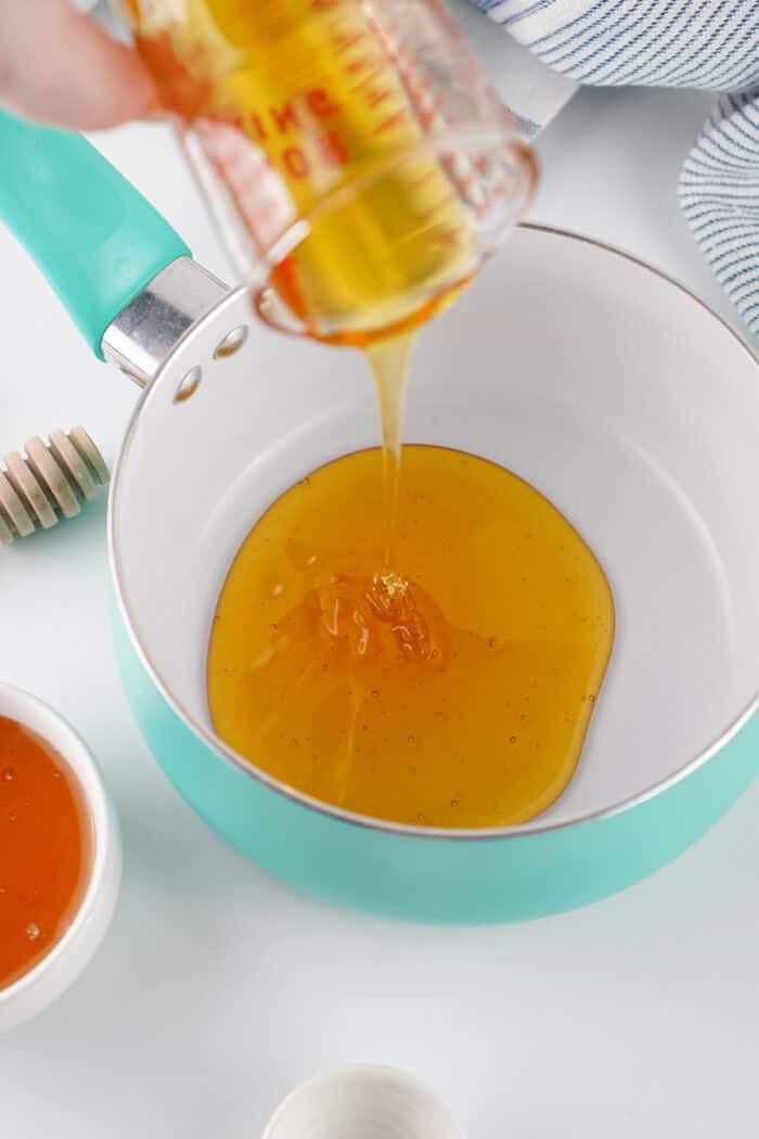 This Hot Honey recipe is made with just 3 ingredients in 7 minutes. It’s ridiculously easy and so much cheaper than buying it at the store. Honey being poured into a saucepan