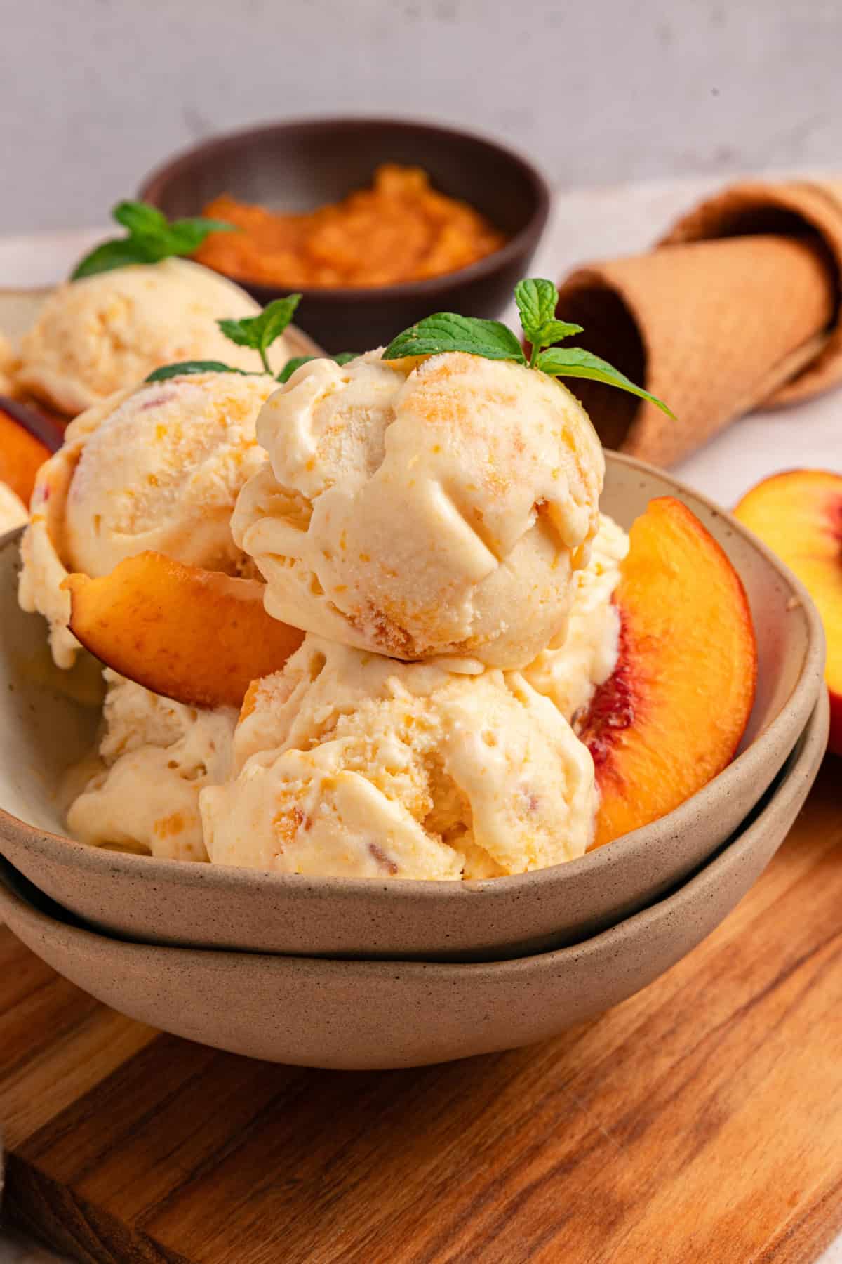 Fresh peaches are turned into a compote and swirled into a mixture of sweetened condensed milk & heavy cream in this No-Churn Peach Ice Cream. peach ice cream scoops in a bowl