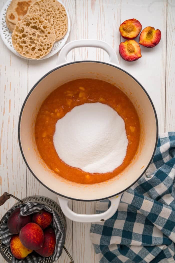 Sugar added to peaches and pectin in a pot