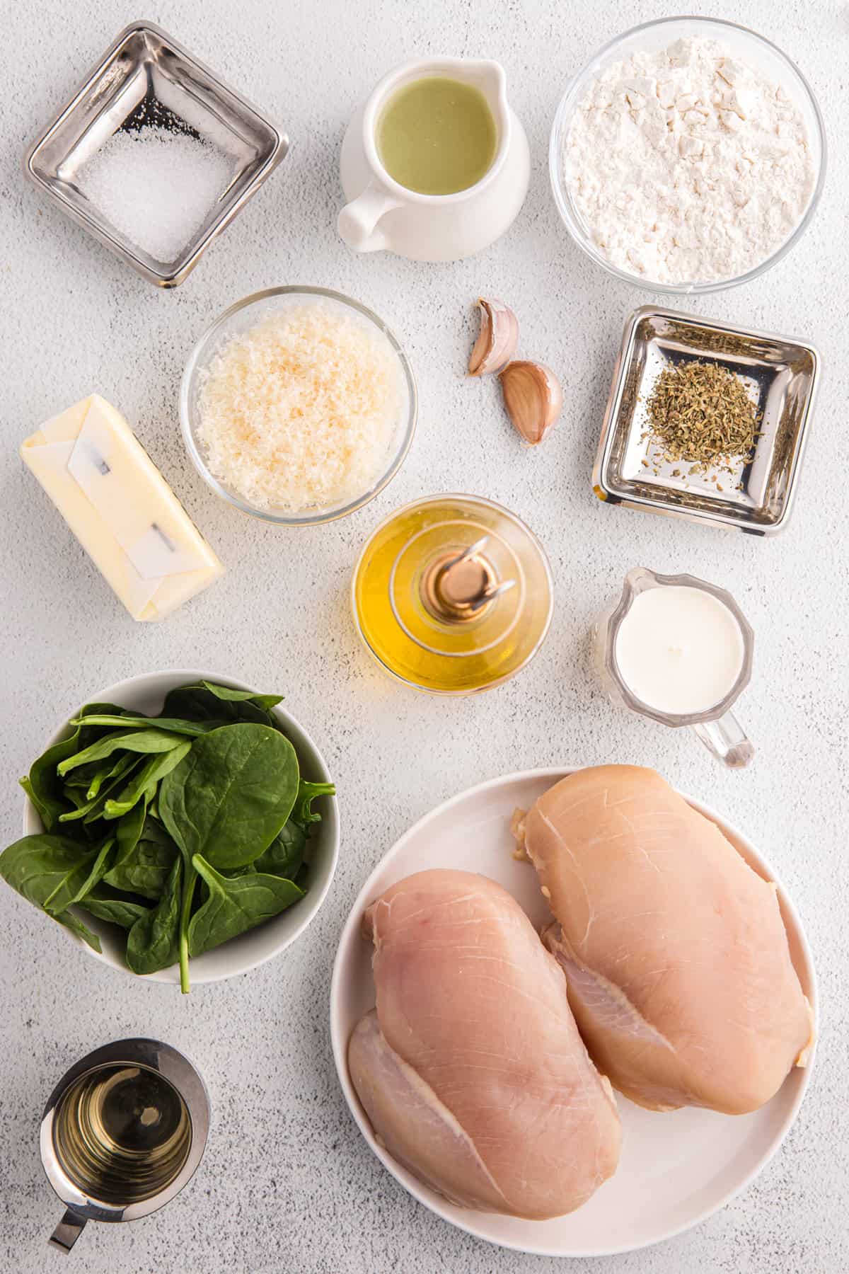 Juicy pan-fried chicken is coated in a creamy, garlicky white wine sauce with spinach and freshly grated parmesan in this Chicken Florentine. Overhead view of ingredients needed to make chicken florentine