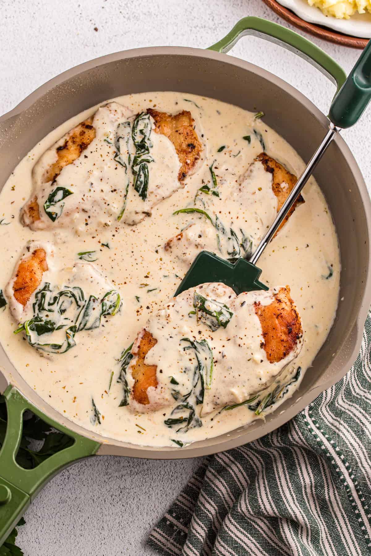 Juicy pan-fried chicken is coated in a creamy, garlicky white wine sauce with spinach and freshly grated parmesan in this Chicken Florentine. Overhead view of a pan of chicken florentine