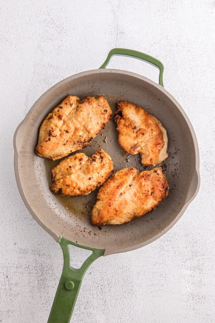 Juicy pan-fried chicken is coated in a creamy, garlicky white wine sauce with spinach and freshly grated parmesan in this Chicken Florentine. Cooked chicken in a pan