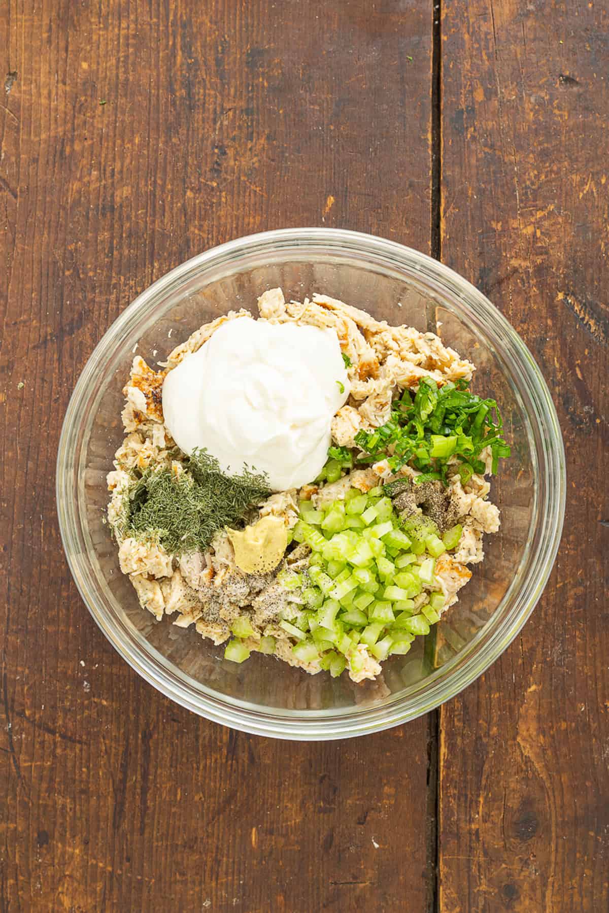 This Classic Chicken Salad Recipe is a simple, no-frills lunch made with shredded chicken, celery, & green onions tossed with mayo and dill. Overhead view of classic chicken salad recipe ingredients in a bowl