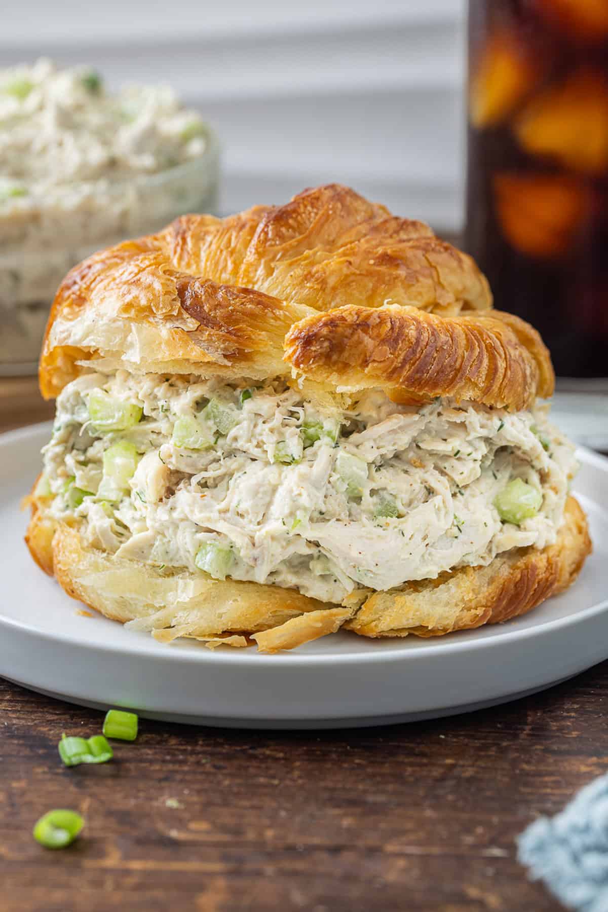 This Classic Chicken Salad Recipe is a simple, no-frills lunch made with shredded chicken, celery, & green onions tossed with mayo and dill. Classic chicken salad on a croissant on a white plate