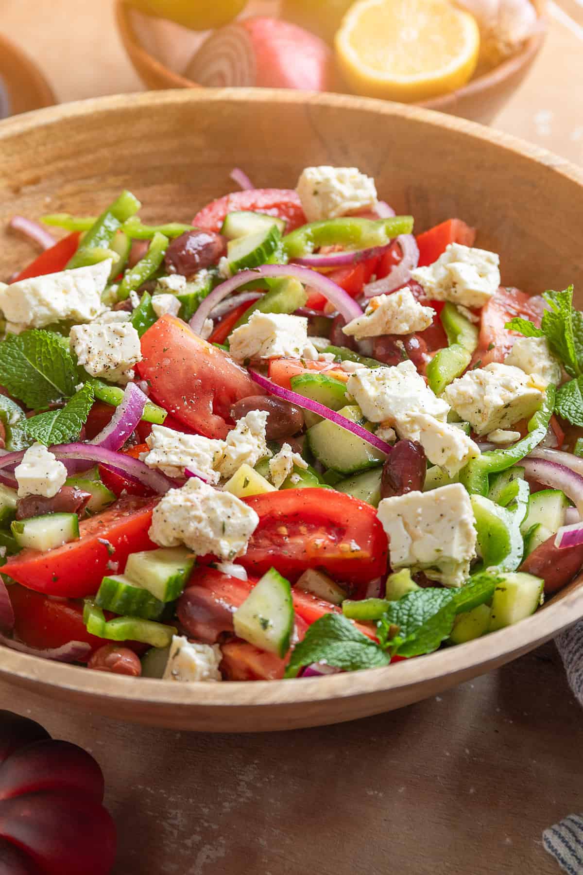 This traditional Greek Salad is made with simple ingredients & bold flavors, like fresh veggies, Kalamata olives, and feta cheese. Greek salad in a wooden bowl