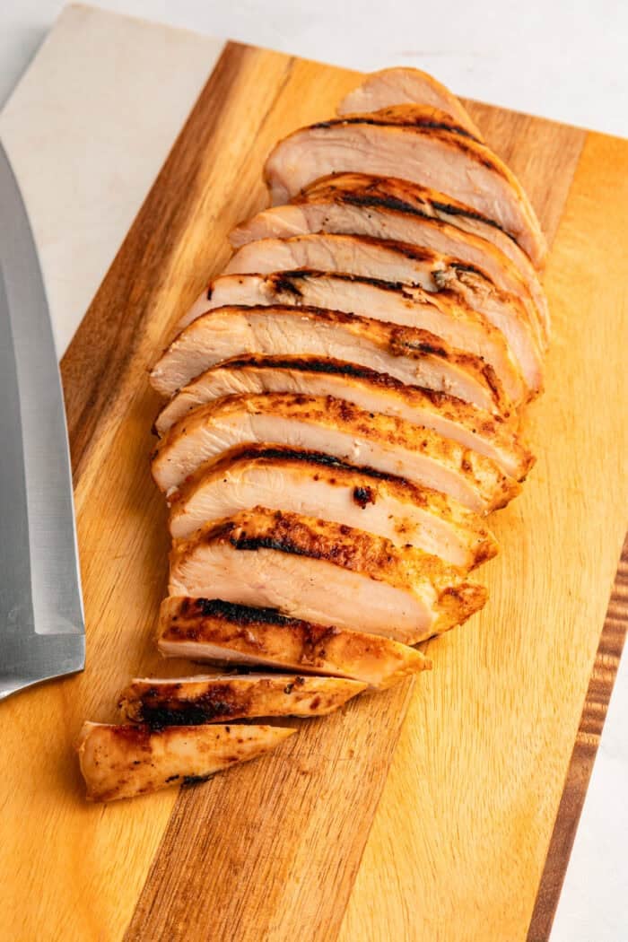 Grilled chicken sits atop a bed of lettuce with cucumber, avocado, tomato, and sharp cheddar cheese in this Honey Mustard Chicken Salad. Close up of a sliced grilled chicken breast