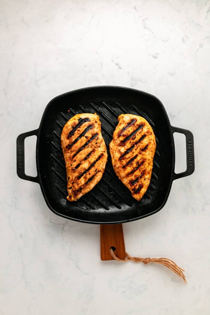 Grilled chicken sits atop a bed of lettuce with cucumber, avocado, tomato, and sharp cheddar cheese in this Honey Mustard Chicken Salad. Chicken breasts on a grill pan
