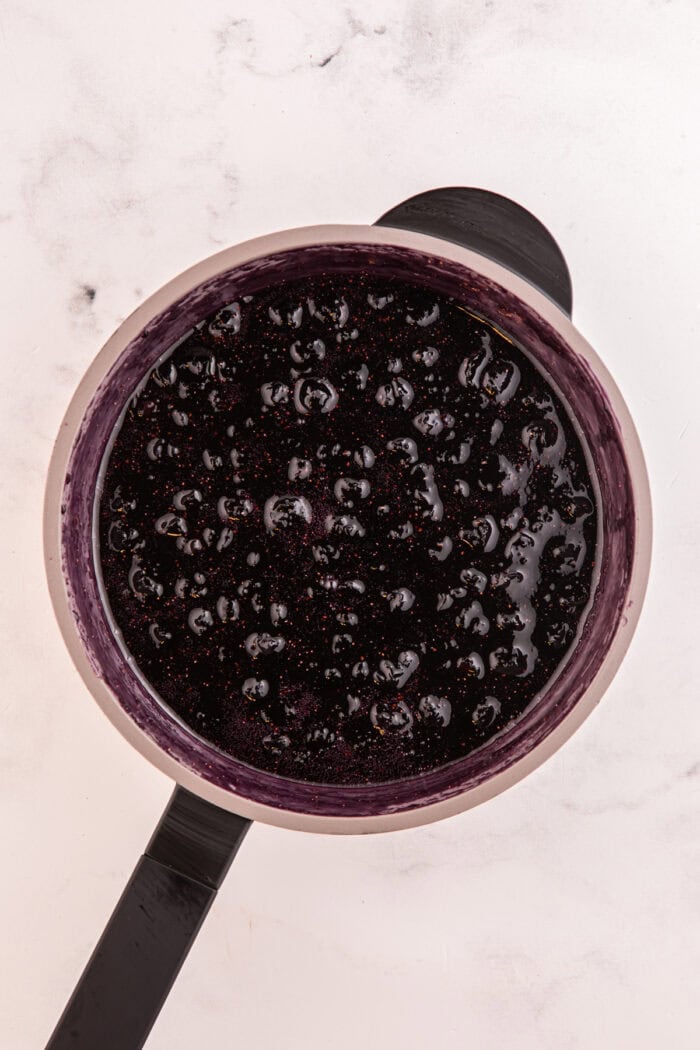 Moist lemon cakes, tangy blueberry cheesecake filling, & tart lemon frosting make up the layers of this Lemon Blueberry Cheesecake Cake. Blueberry puree in a pan