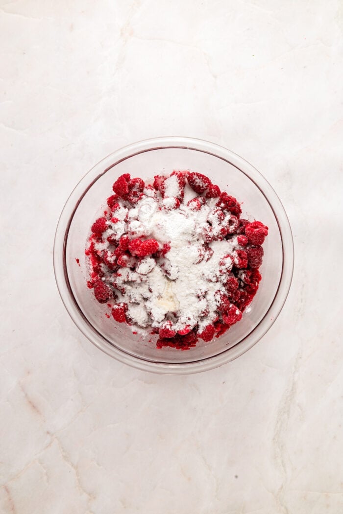This rustic Raspberry Cobbler recipe is made with a jammy fruit filling and a golden, biscuit-style topping. Quick & easy! Raspberries, sugar, and other filling ingredients in a bowl
