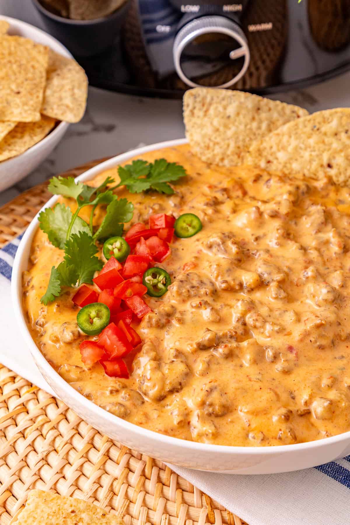 Cheesy Sausage Dip turns ground sausage, Velveeta, cream cheese, and Rotel into a creamy, cheesy, and irresistible party dip in just minutes. A bowl of cheesy sausage dip in front of the slow cooker