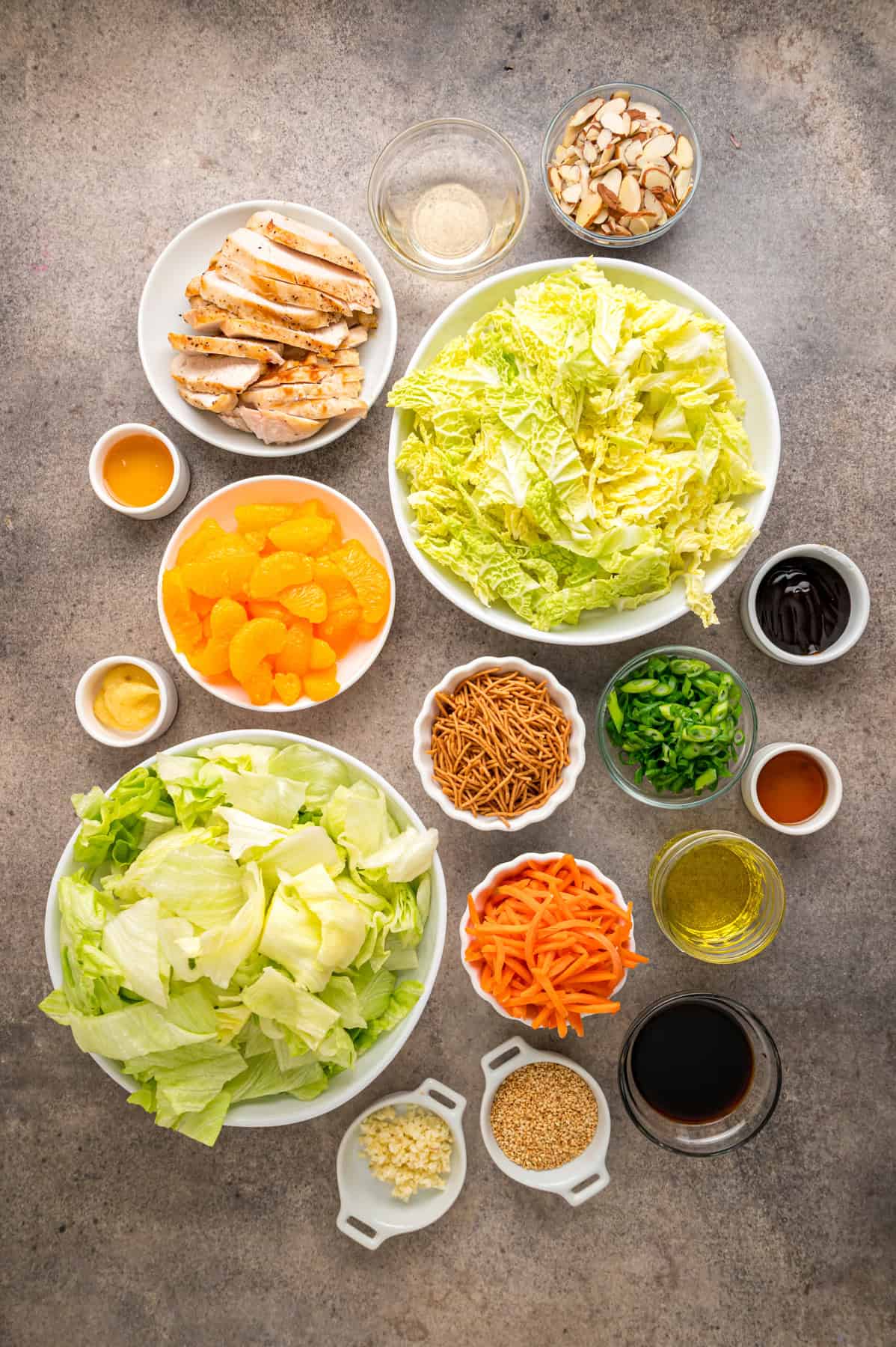 Grilled chicken, crunchy veggies, and mandarin oranges are tossed in a ginger sesame dressing in this easy Chinese Chicken Salad recipe. Overhead view of ingredients needed to make Chinese chicken salad