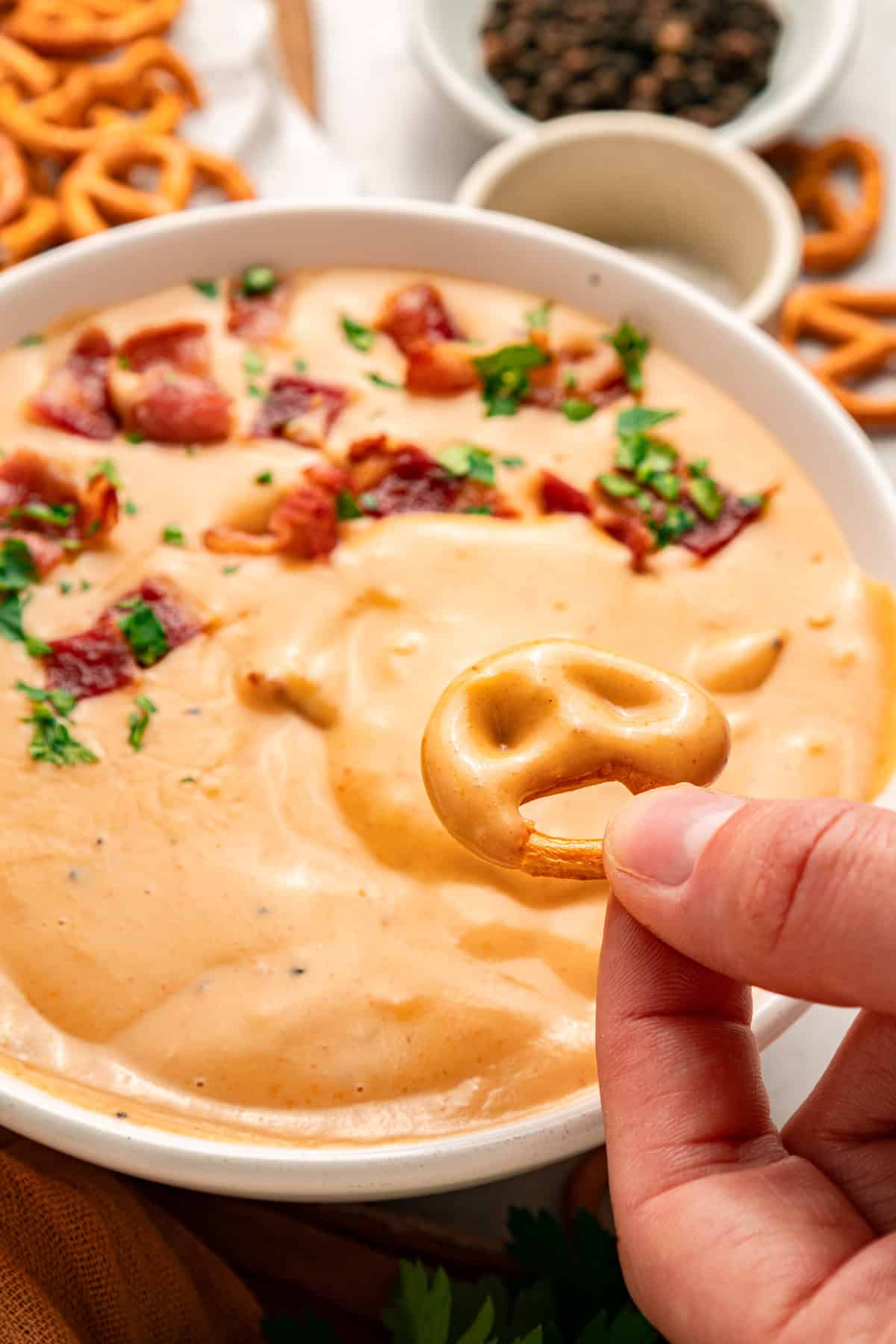 This Beer Cheese Dip is warm, sharp, and just a little smoky, with a combination of cheddar & gruyere and your favorite beer. A hand dipping a pretzel into beer cheese
