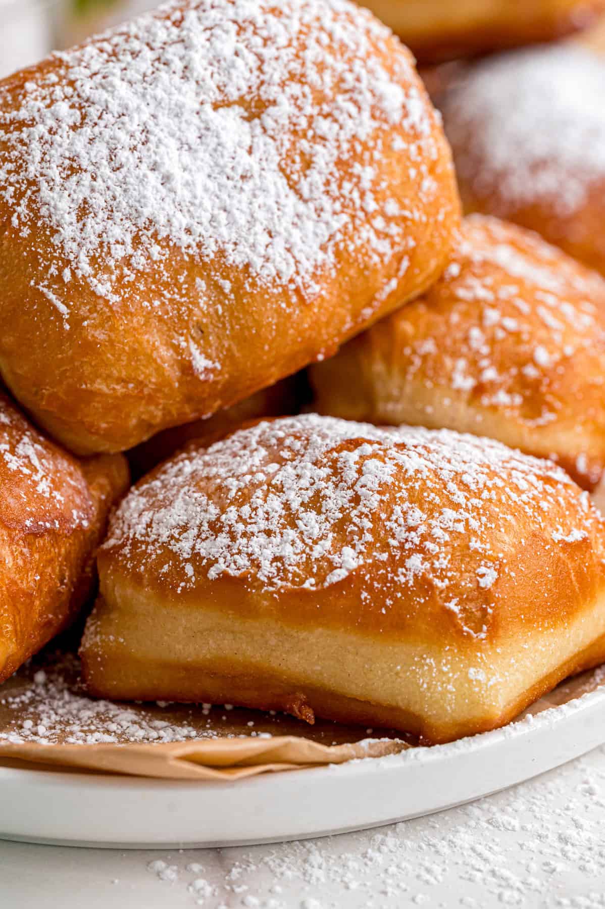 This Beignets recipe is an easy homemade version of the popular New Orleans fried square donuts. Soft & fluffy! A plate of homemade beignets