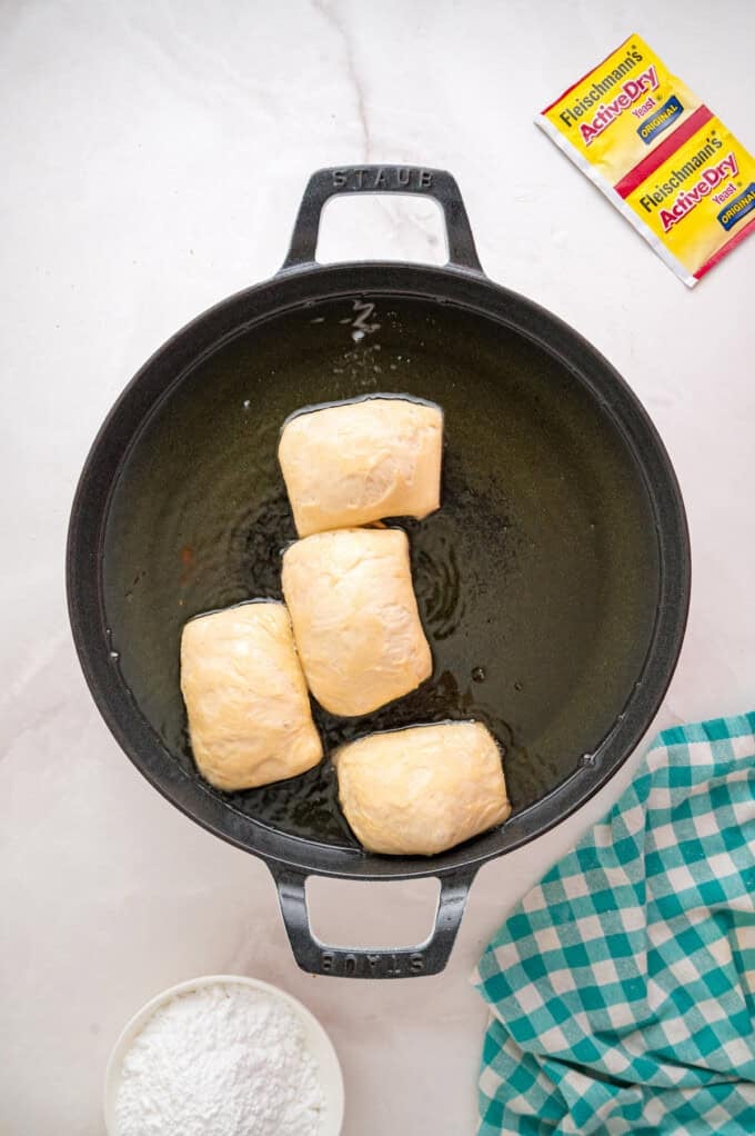 This Beignets recipe is an easy homemade version of the popular New Orleans fried square donuts. Soft & fluffy! Beignets frying in a pan