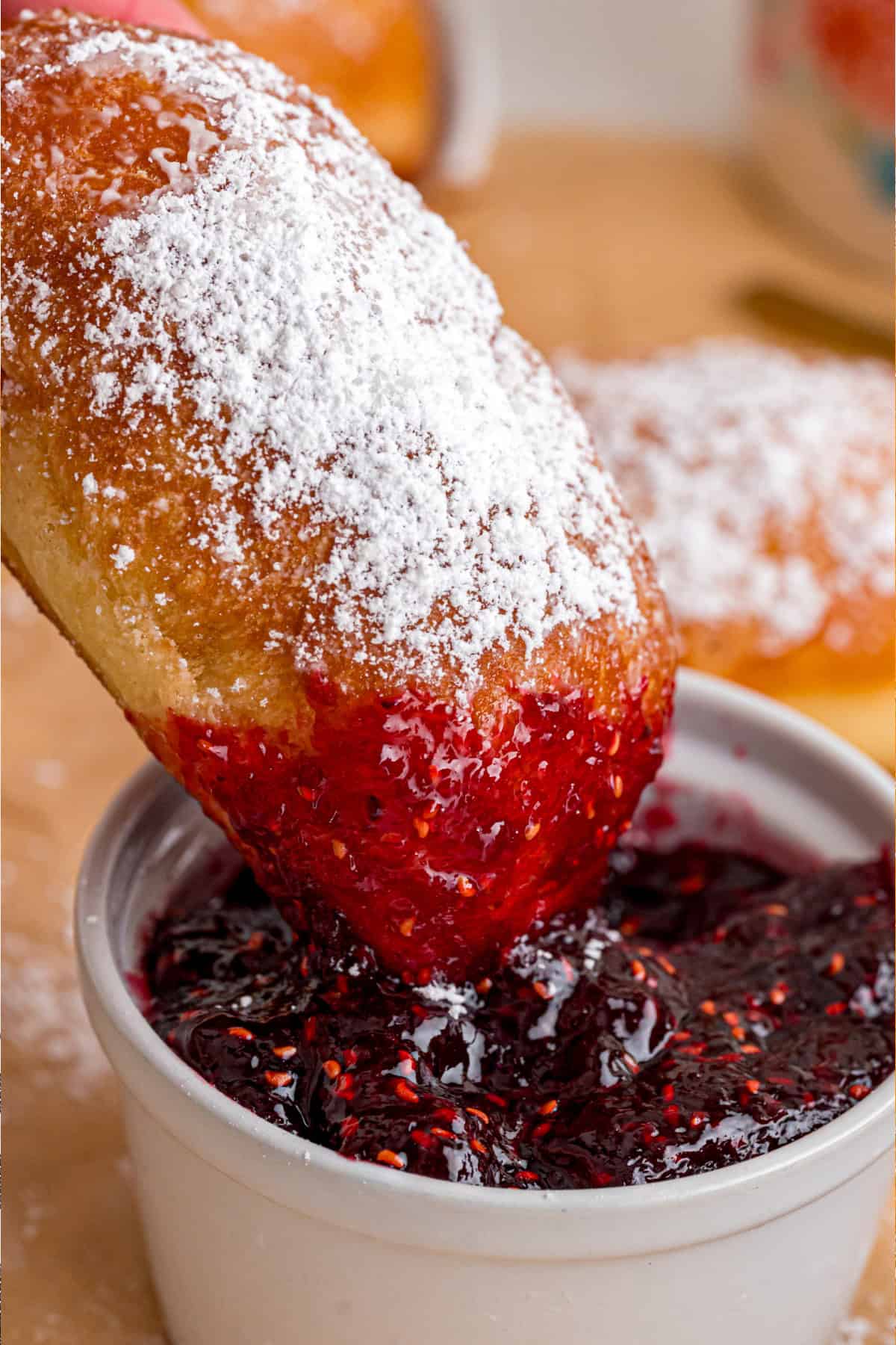 This Beignets recipe is an easy homemade version of the popular New Orleans fried square donuts. Soft & fluffy! Dipping a beignet in raspberry sauce