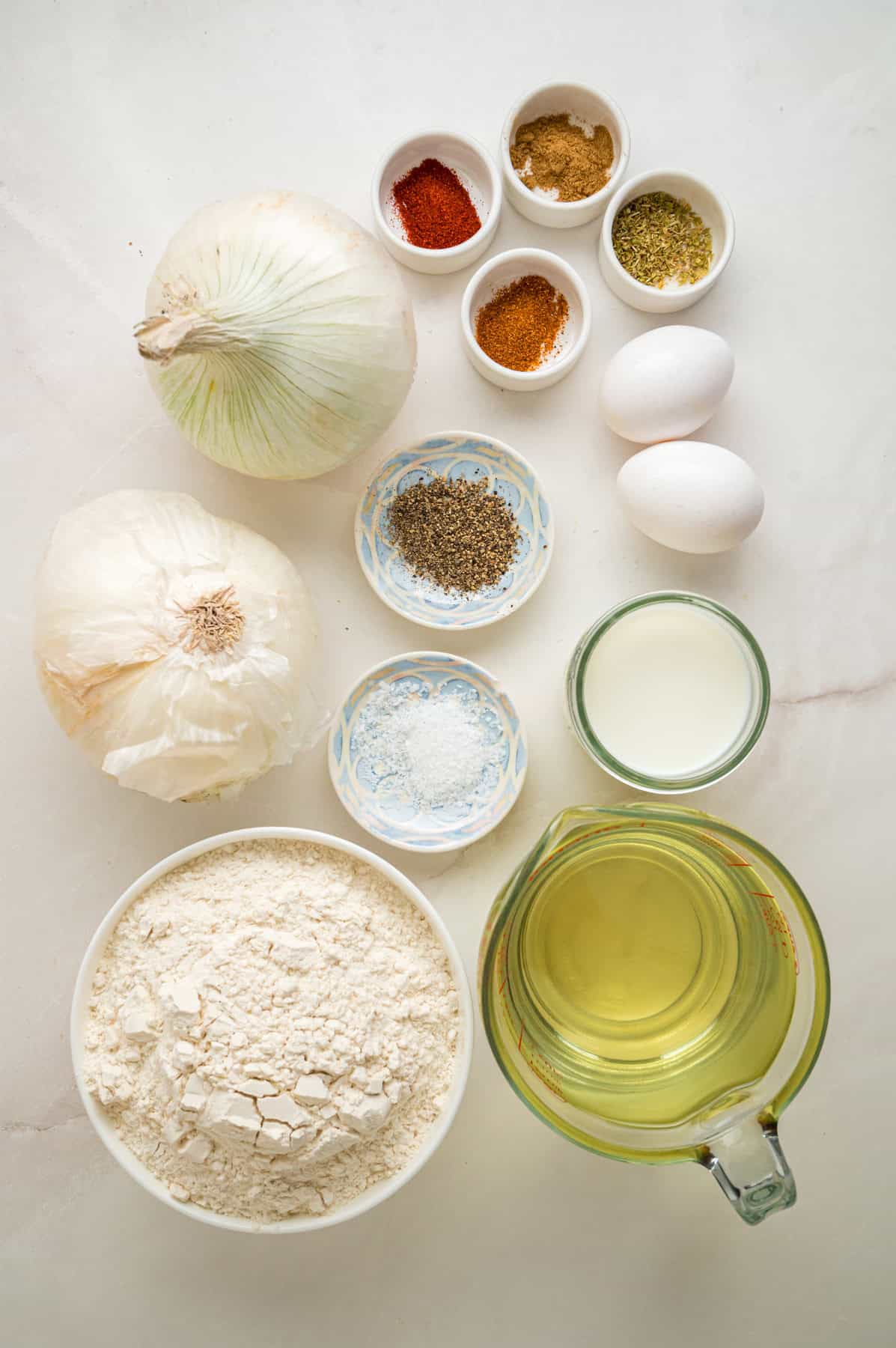 Onions are coated in a seasoned batter, then deep-fried to crispy, golden perfection in this Blooming Onion recipe. Overhead view of ingredients to make blooming onions
