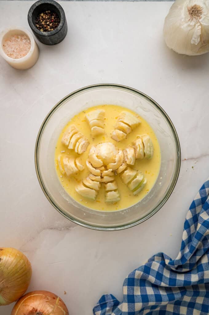 Onions are coated in a seasoned batter, then deep-fried to crispy, golden perfection in this Blooming Onion recipe. An onion in an egg wash in a bowl