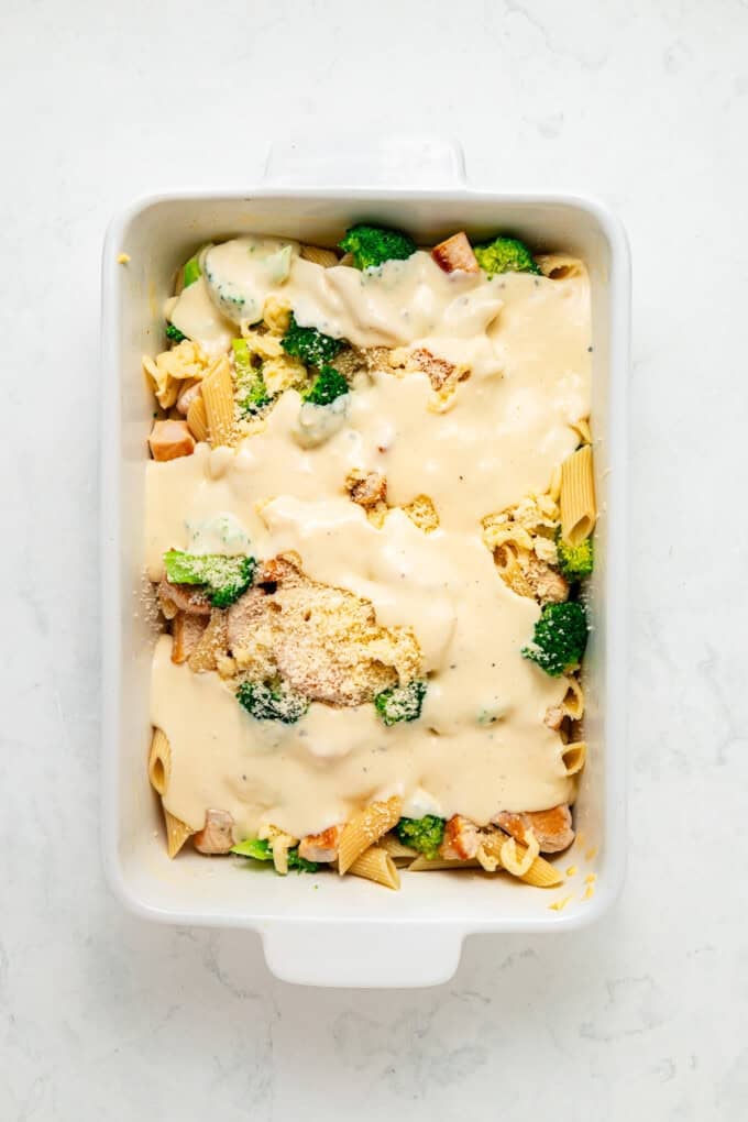 Tender penne, shredded chicken, and broccoli are tossed in a from-scratch sauce that's rich and garlicky in this Chicken Broccoli Alfredo. Chicken, noodles, and broccoli in a baking dish with alfredo sauce on top