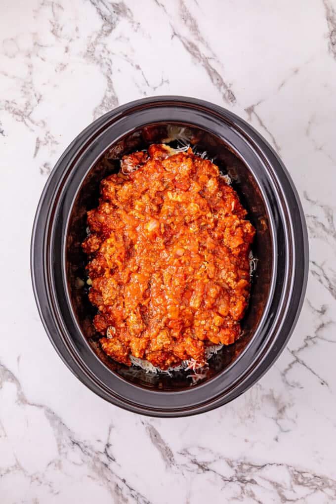 Ground beef with pasta sauce, frozen ravioli, and shredded cheese are layered to make this Crockpot Ravioli Lasagna. Meat sauce on top of the layers in the crockpot