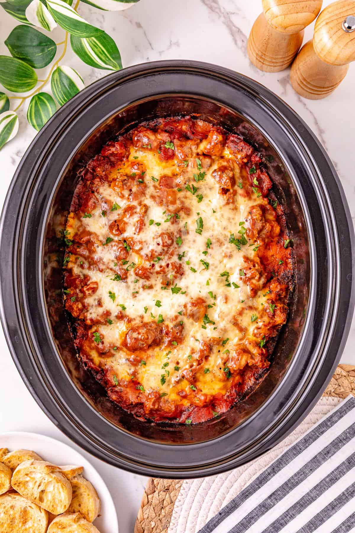Ground beef with pasta sauce, frozen ravioli, and shredded cheese are layered to make this Crockpot Ravioli Lasagna. Overhead view of ravioli lasagna in a crockpot